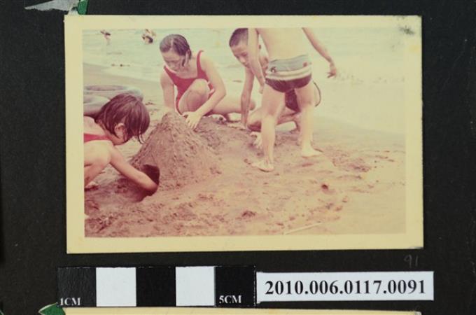 一女子與3位孩童在沙灘堆沙堆的照片 (共1張)